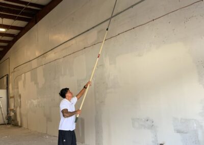 preparing a tall wall for painting with an electric sander