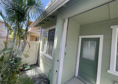 AFTER - exterior painting of a green house in Hawaii by Mckeague Drywall showing the back door