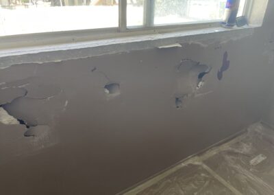 photo showing how Mckeague Drywall LLC repairs damaged drywall including protecting the floor from debris with a plastic cover that is taped down