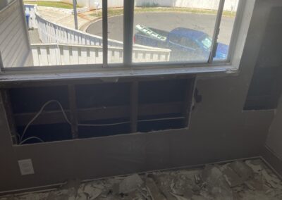 photo showing how Mckeague Drywall LLC repairs damaged drywall with several areas of damaged drywall now cut away and resting on the plastic cover ready to be thrown away
